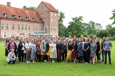 Gruppfoto av 50 personer på en gräsmatta framför ett slott.